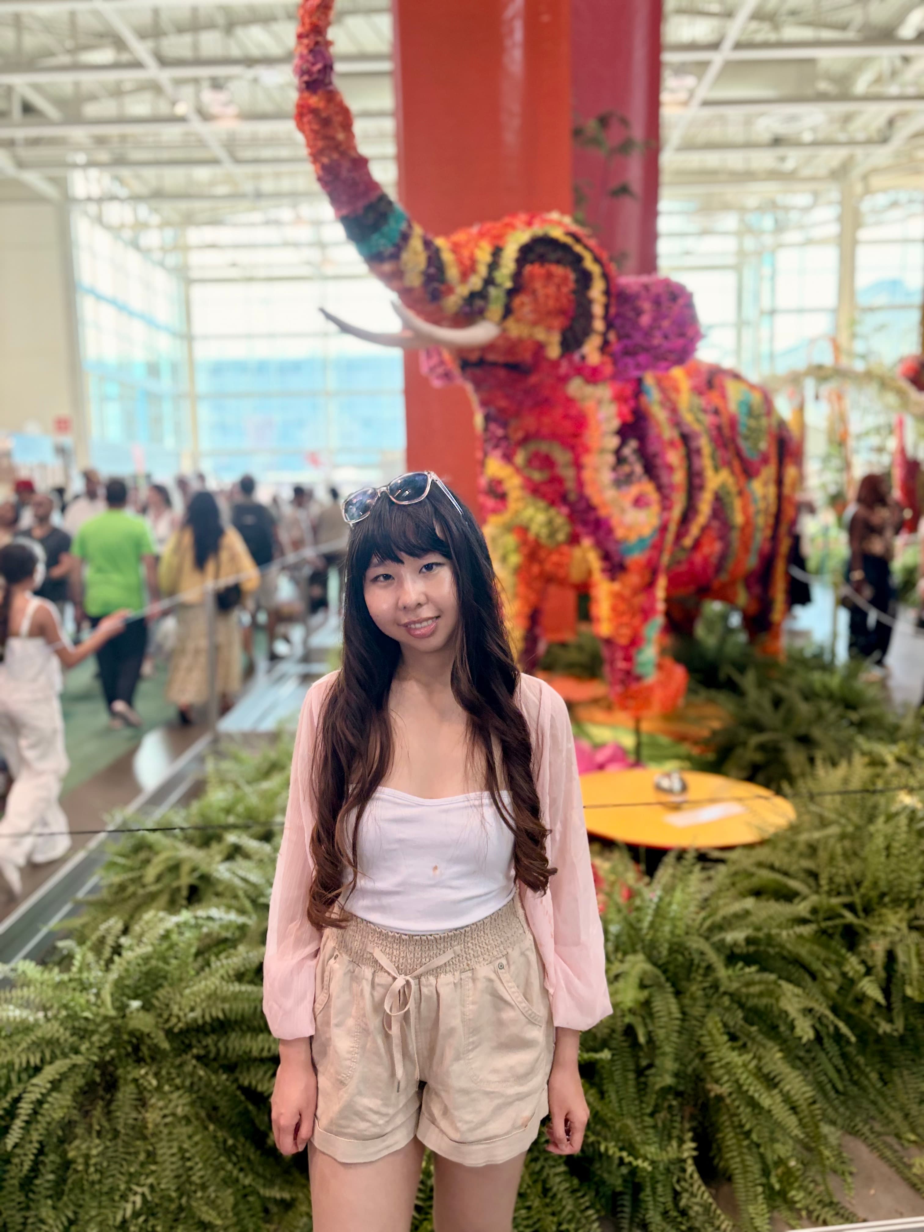 Amy in front of a flower-covered elephant sculpture